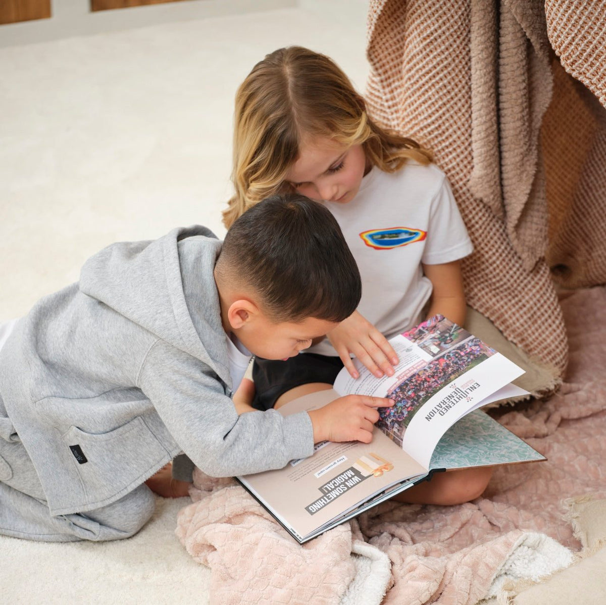 A girl and a boy on a cozy rug, reading an Enlightened Generation book together