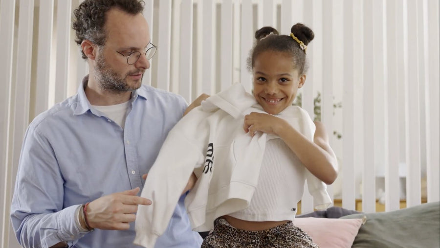 A smiling girl holds up her new white Leaf Sheep hoodie next to her dad